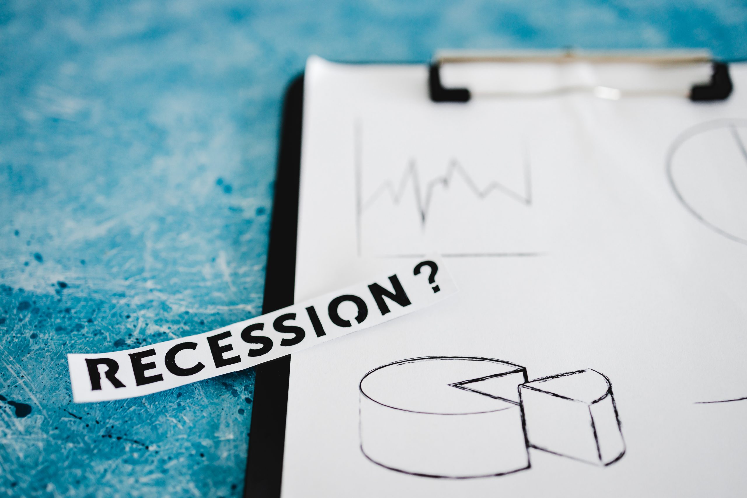 recession text next to clipboard showing a multitude of stas and